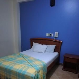 Dormitorio azul con cama y pared azul en Hotel Murcia, en Guayaquil