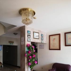 a living room with a chandelier and pink flowers at Hotel Murcia in Guayaquil