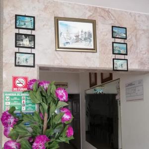 un jarrón de flores rosas en una pared con fotos en Hotel Murcia, en Guayaquil