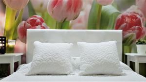a white bed with two pillows and pink tulips at Home Sweet Home in Arona