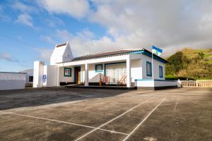 a white building with a parking lot in front of it at Quinta do Oeste in Doze Ribeiras