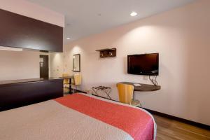a hotel room with a bed and a tv on the wall at El Paso Inn in Ysleta