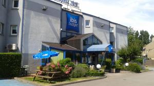Ibis budget Dunkerque Grande Synthe في غراند-سانت: مبنى ازرق به طاولات ومظلات