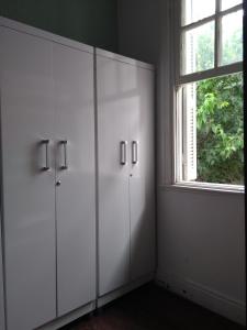um quarto branco com armários brancos e uma janela em Hostel Santana - Metrô Santana em São Paulo