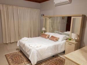 a bedroom with a white bed with a large mirror at RY Courtyard in Oshakati