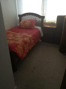 1 dormitorio con 1 cama con manta roja y ventana en Teatinos 690, en Santiago