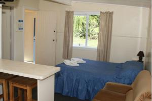 a bedroom with a blue bed and a window at Alma Motel in Oamaru +30 photos