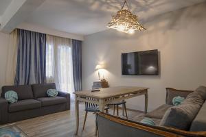 a living room with a table and a couch and a tv at Sali Boutique hotel in Alexandroupoli
