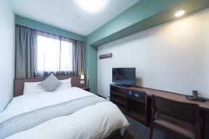 a bedroom with a bed and a desk with a television at Myoujin-no-Yu Dormy Inn Premium Kanda in Tokyo