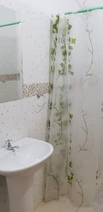 a bathroom with a sink and a shower curtain with vines at Helecho's Hostal in Encarnación