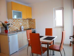 eine Küche mit einem Tisch und Stühlen sowie eine Küche mit gelben Schränken in der Unterkunft Apartments Harmonija in Baška Voda