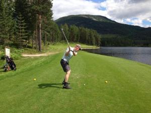 a man swinging a golf club on a golf course at Vrådal Panorama - Tiuråsvegen 39 in Vradal