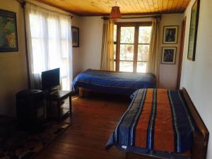 a bedroom with two beds and a television and a window at Cabañas La Magia de Isla Negra in Isla Negra