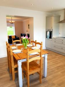 a wooden dining room table with chairs and a kitchen at Cathleen's Cottage in Newry