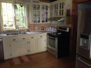 a kitchen with white cabinets and a black appliances at Gite la Tourelle du Cap in La Malbaie