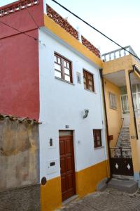 a white and orange building with a red door at Casa Rústica da Lavandeira in Valongo dos Azeites