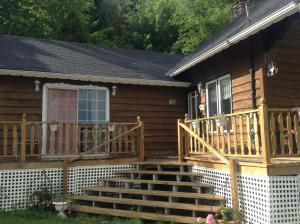 a house with a wooden deck and stairs at Gite la Tourelle du Cap in La Malbaie