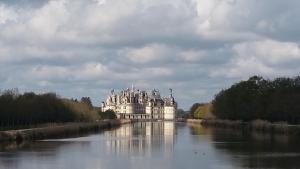 a large white building sitting on top of a river at Chambre d'hôte Montlivault / Chambord in Montlivault +11 photos