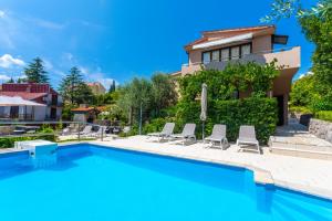 a swimming pool with chairs and a house at APARTMENTS HOUSE BARBARA 2 in Kornić