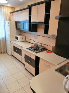 La cuisine est équipée de placards blancs et d'un four avec plaques de cuisson. dans l'établissement Big Apartment in Rivne center, à Rivne