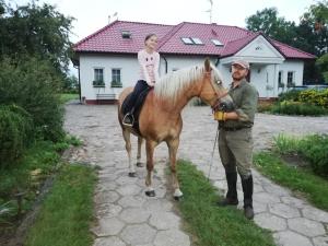 a man standing next to a horse with a girl on it at Babie Lato in Włodarka