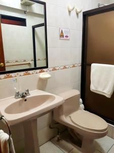 a bathroom with a sink and a toilet and a mirror at Hotel Las Americas in Quetzaltenango