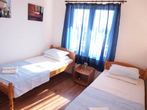 Cette chambre comprend deux lits et une fenêtre avec des rideaux bleus. dans l'établissement Apartments Adria, à Orebić