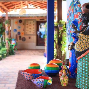 a table with colorful bowls and vases on it at Pousada Murici in Barreirinhas