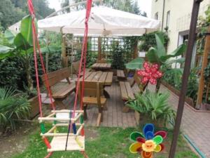 eine Schaukel in einem Garten mit einem Tisch und einem Sonnenschirm in der Unterkunft Pension Strohbach in Sebnitz
