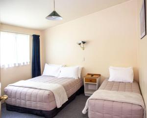 two beds in a small room with a window at Goldmine Motel in Waihi