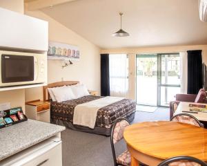 Cette petite chambre comprend un lit et une table. dans l'établissement Goldmine Motel, à Waihi