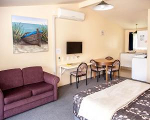 a room with a couch and a table and a kitchen at Goldmine Motel in Waihi