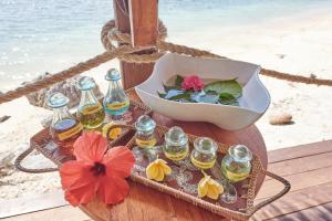 a tray with bottles of oil and a bowl of flowers at Cocotinos Sekotong Lombok in Sekotong