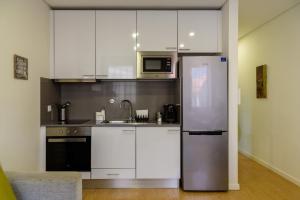 a kitchen with white cabinets and a stainless steel refrigerator at Cativo Flat in Porto