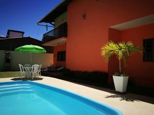 una piscina con una sombrilla verde junto a una casa en Casa Melo e Azevedo, en São Miguel dos Milagres