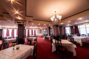 un restaurant avec des tables et des chaises blanches et un lustre dans l'établissement Hotel AmaDeus, à Focşani