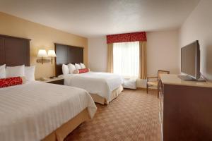 a hotel room with two beds and a flat screen tv at Cortona Inn and Suites Anaheim Resort in Anaheim