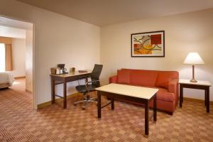 a hotel room with a couch and a desk at Cortona Inn and Suites Anaheim Resort in Anaheim