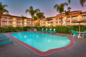 a large swimming pool with chairs and a hotel at Cortona Inn and Suites Anaheim Resort in Anaheim