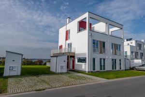 una casa blanca con una puerta roja en una calle en Saltkrokan, en Olpenitz