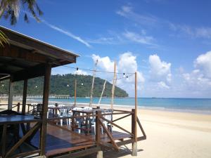 a beach with tables and chairs and the ocean at Rainbow Tioman Cottage in Kampong Juara