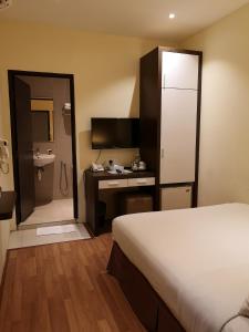 a hotel room with a bed and a desk and a bathroom at The V Hotel in Kuantan