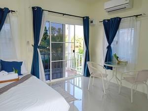 ein Schlafzimmer mit einem Bett und einen Balkon mit einem Tisch und Stühlen in der Unterkunft Ban Ing Suan in Samutprakarn