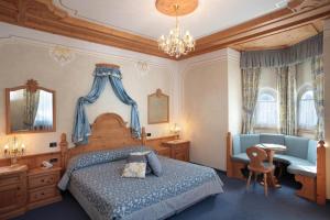 a bedroom with a bed and a desk and a chair at Hotel Colbricon Beauty & Relax in San Martino di Castrozza