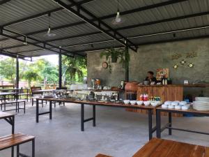 a restaurant with tables and a person in the background at Kodaun River Kwai Resort in Kanchanaburi City