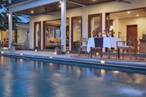 a dining table and chairs next to a pool at D'Legon Luxury Villas in Ubud
