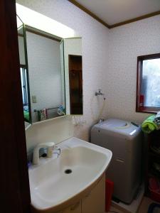 ein Badezimmer mit einem Waschbecken, einem WC und einem Spiegel in der Unterkunft Ikkenya Kitagata in Okayama