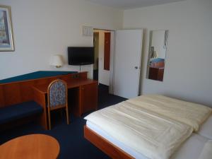 een slaapkamer met een bed, een bureau en een stoel bij Centralhotel Ratingen in Ratingen