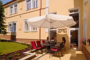 a man and woman sitting at a table under an umbrella at Penzión Donet in Bratislava