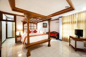 Bali Taman Beach Resort & Spa Lovina في لوفينا: غرفة نوم بسرير مظلة وتلفزيون